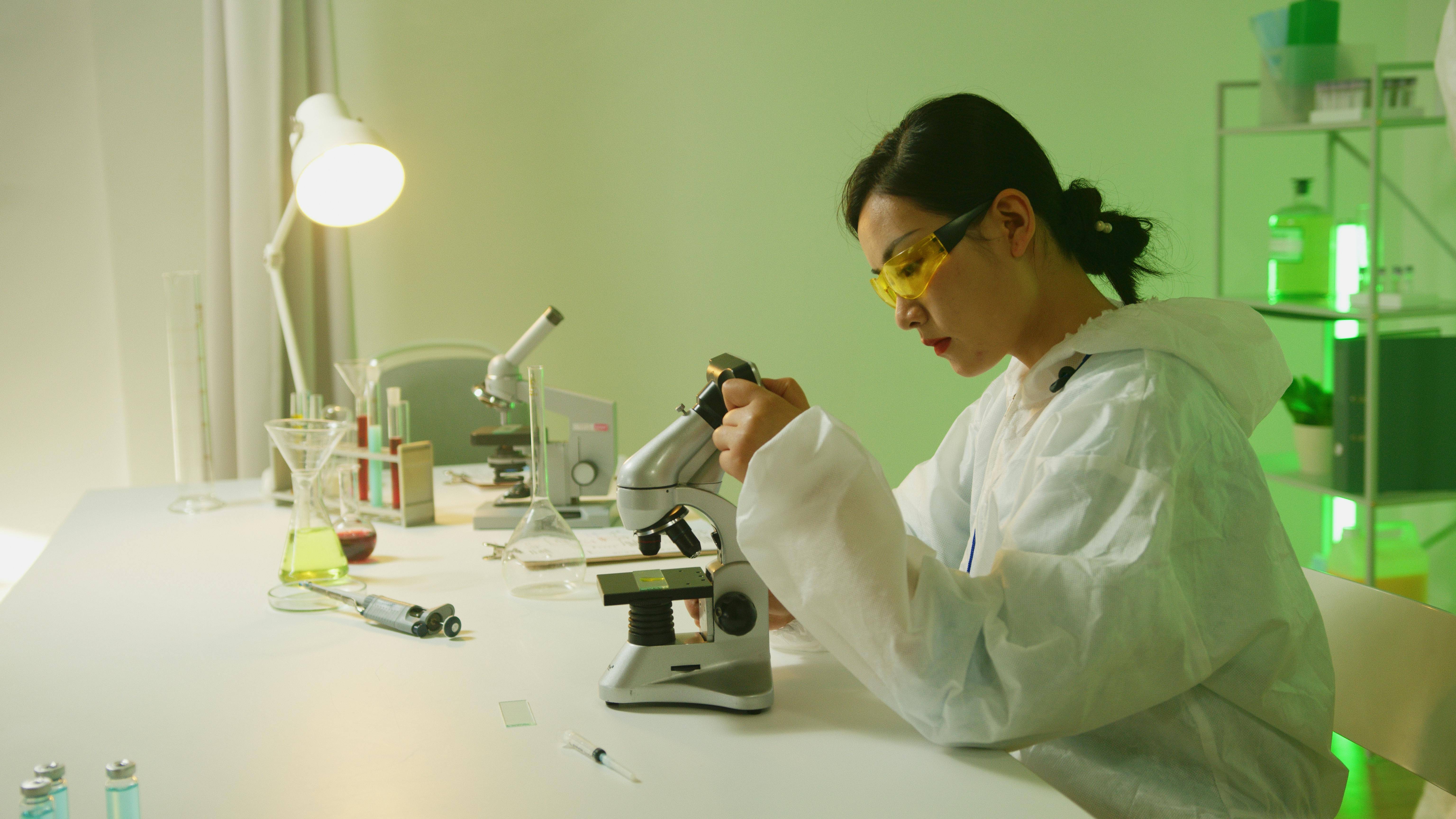 Woman working in a laboratory and analyzing slides under a microscope